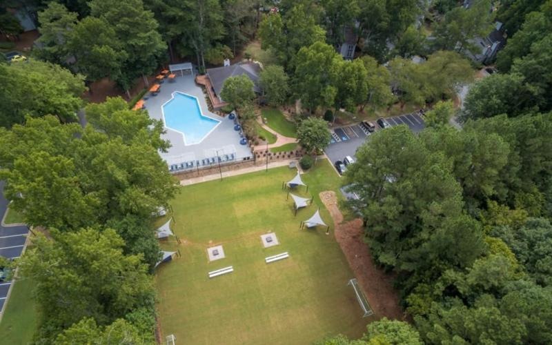 an aerial view of a pool and grassy area with trees